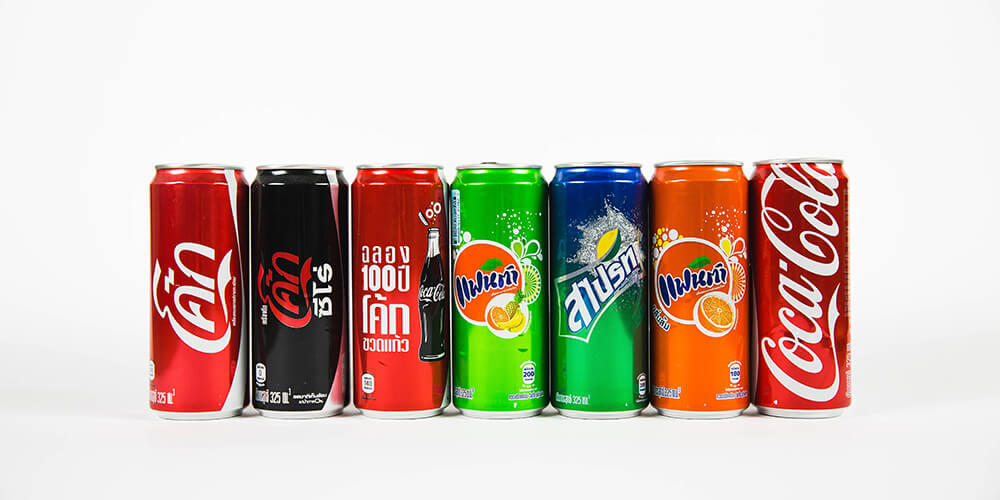7 cans of fizzy drinks with different branding