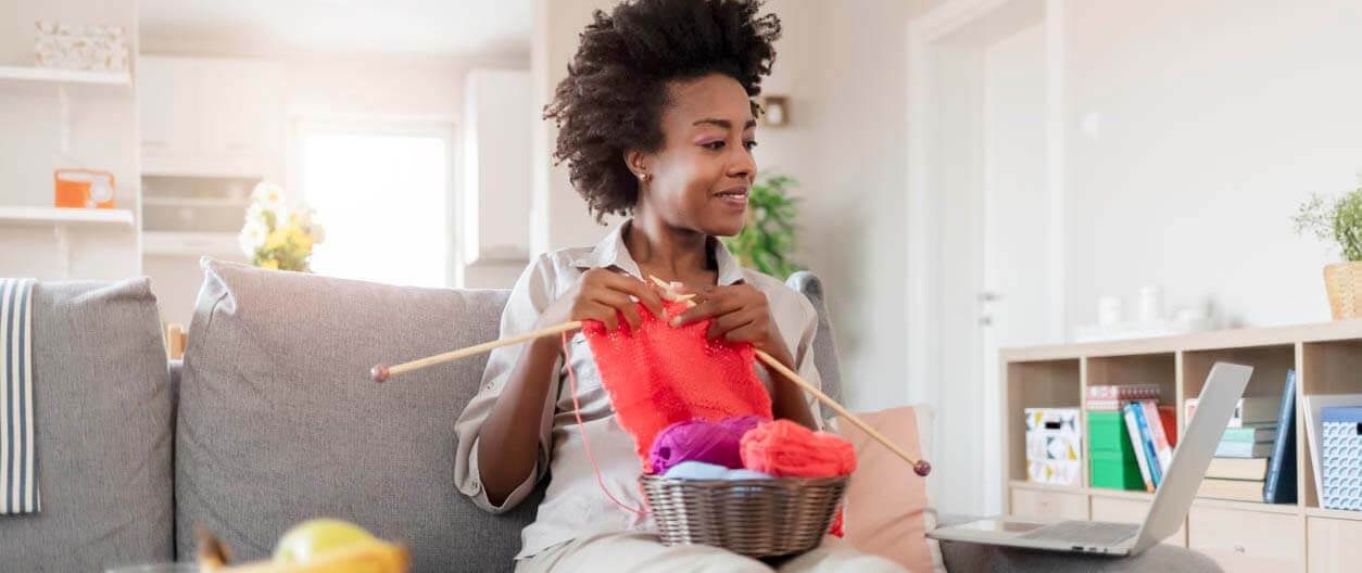 Woman relaxing on a couch while knitting.