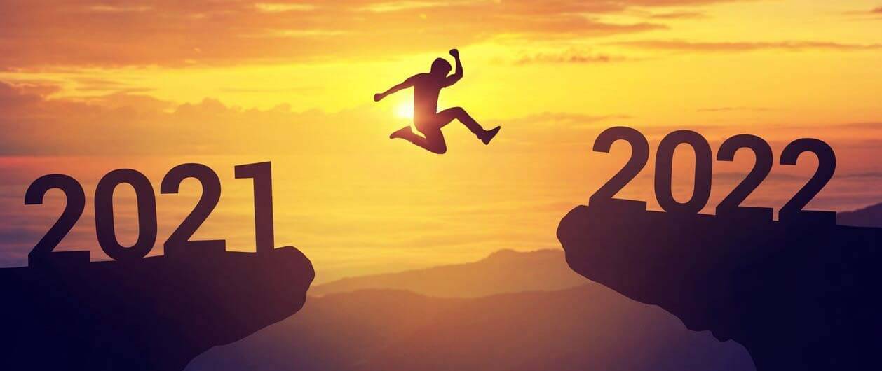 Man jumping from cliff edge saying 2021 to another saying 2022