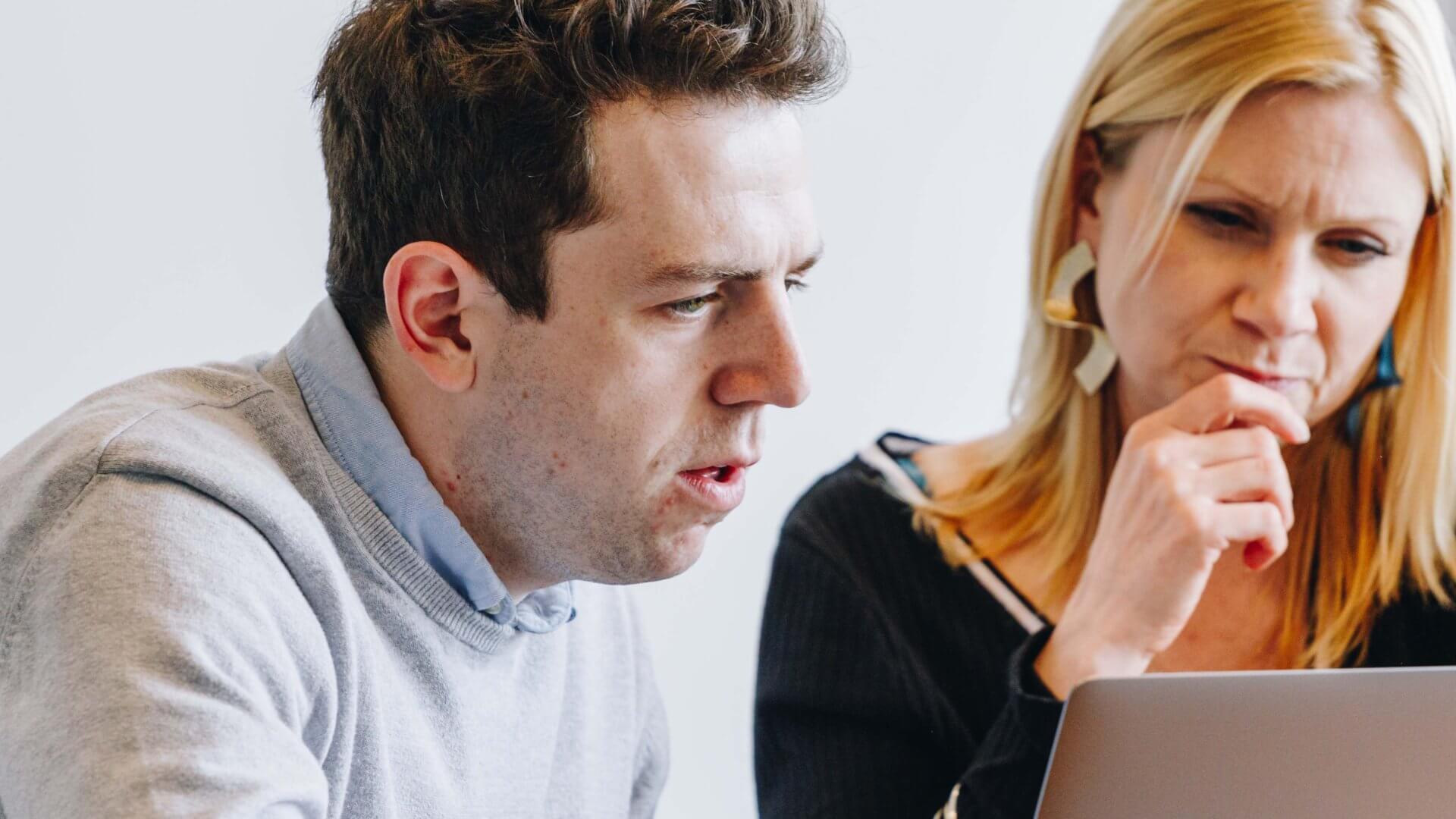 Man and woman sat in front of a laptop debating a work situation