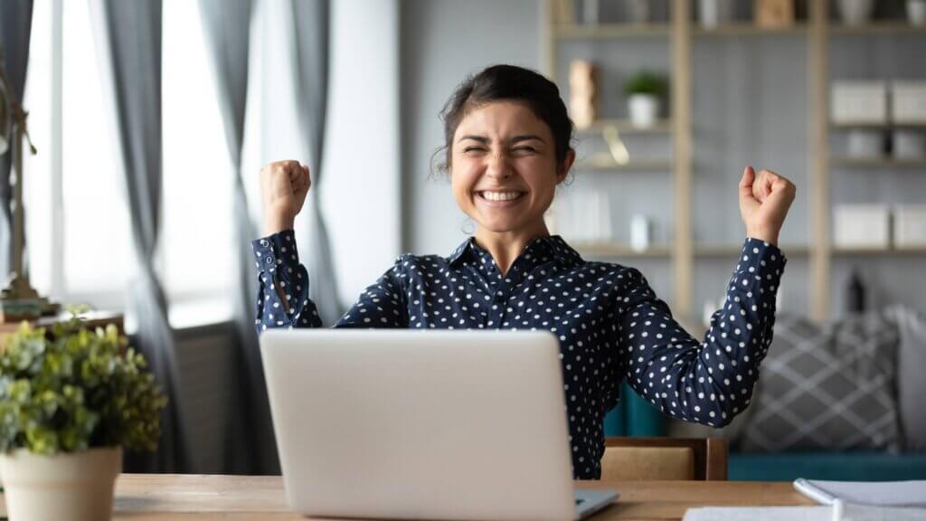 A women sat in front of a laptop cheering