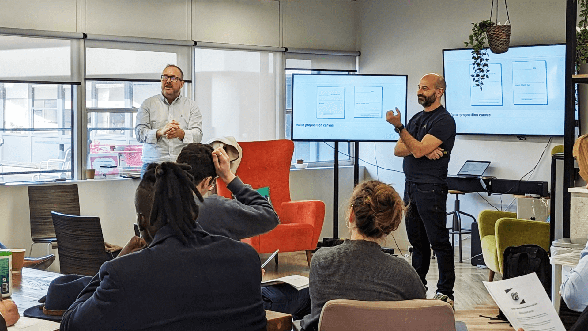 Gathering of agency professionals around a tv giving a talk