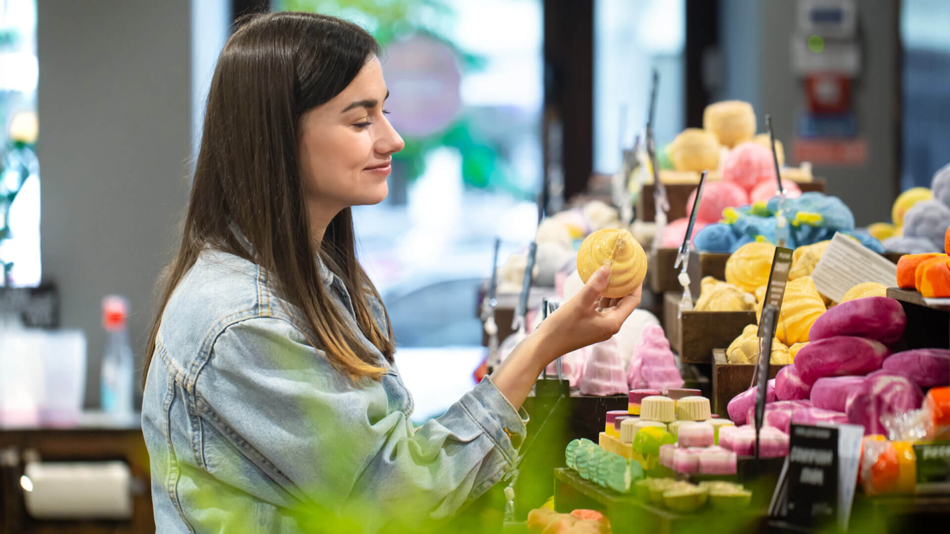 A woman examines a colorful display of various soap products in a retail setting, showcasing her interest in personal care items.